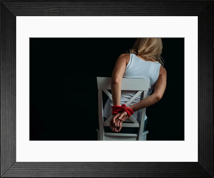 Framed Print : Back view of woman with tied hands sitting on white chair isolated on black Framed Print : Back view of woman with tied hands sitting on white chair isolated on black