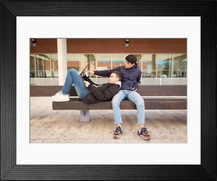 Framed Print : couple two gay university students together on a bench using laptop computer