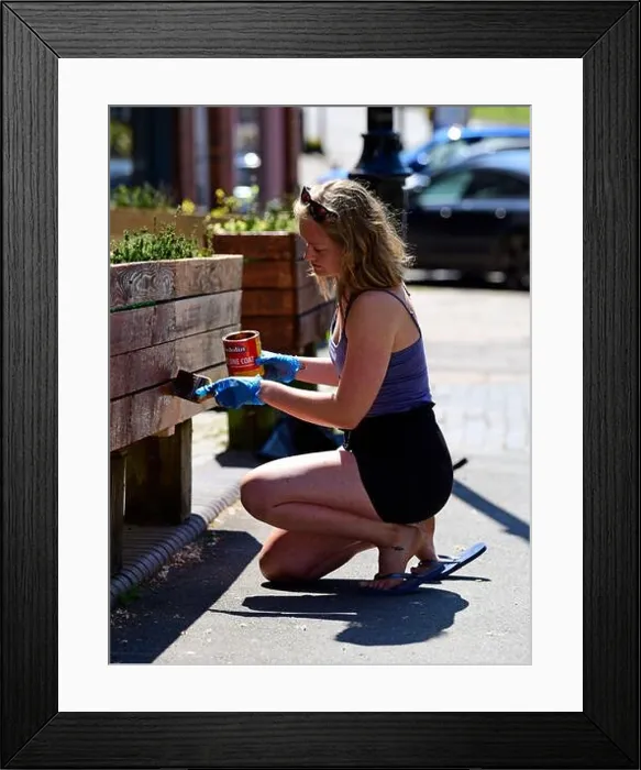 Framed Print : Woman painting flower bed box outside her shop during Coronavirus (COVID-19) pandemic, Haslemere, Surrey, UK