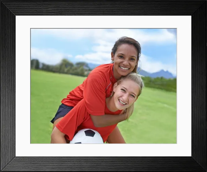 Framed Print : Best friends and teammates. Shot of a female soccer player carrying her teammate on her back Framed Print : Best friends and teammates. Shot of a female soccer player carrying her teammate on her back