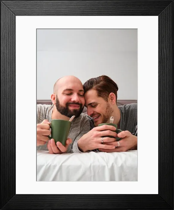 Framed Print : Gay couple in love drinking coffee in bed together Framed Print : Gay couple in love drinking coffee in bed together