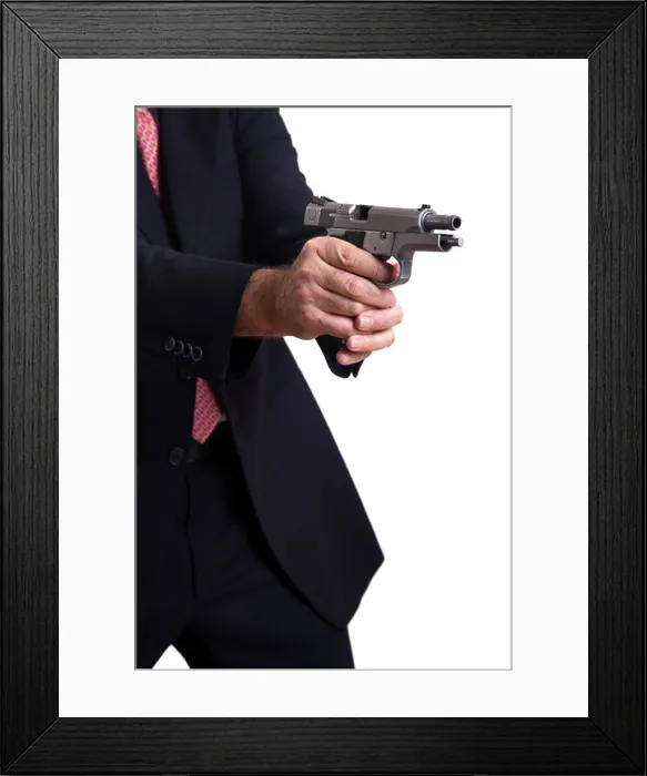 Framed Print : A mature adult man wearing suit holding 9mm gun both hands right in middle firing shot gun's latch in backwards Framed Print : A mature adult man wearing suit holding 9mm gun both hands right in middle firing shot gun's latch in backwards