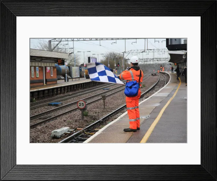 Framed Print : Railway worker wearing high visibility orange clothing holds blue and white checkered safety flag