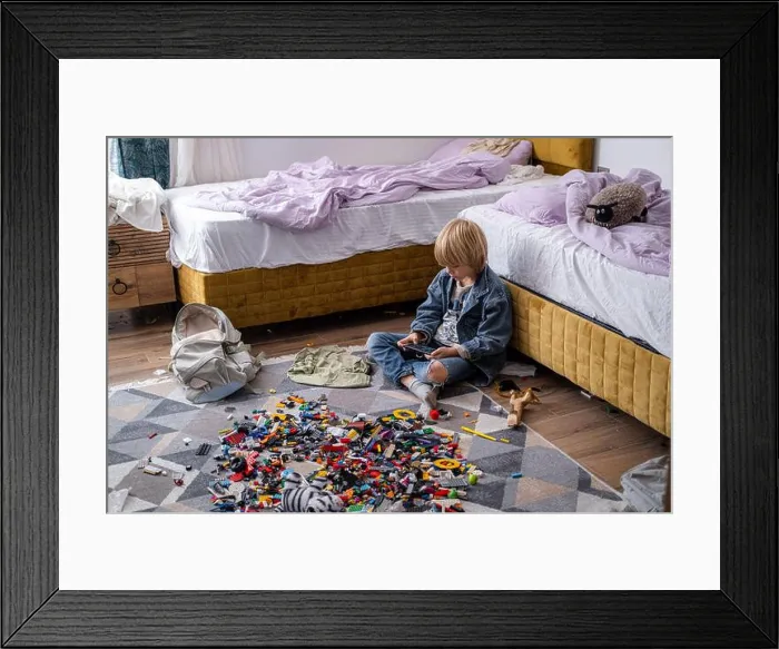 Framed Print : boy using phone, playing phone games in messy childrens room Framed Print : boy using phone, playing phone games in messy childrens room