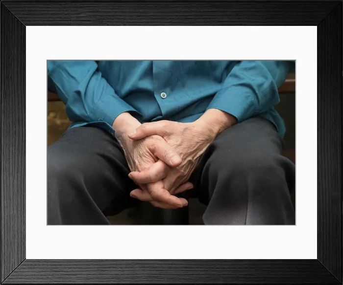 Framed Print : A man sitting with hands on the knees and fingers locked Framed Print : A man sitting with hands on the knees and fingers locked