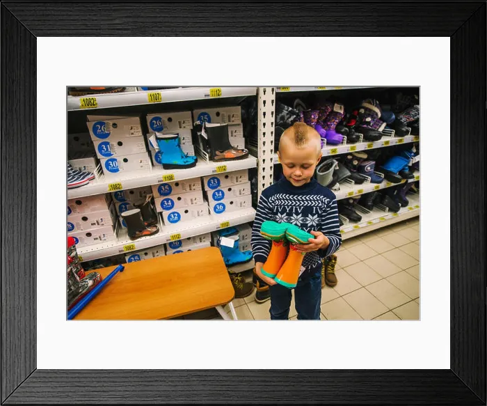 Framed Print : Caucasian boy admiring boots in store Framed Print : Caucasian boy admiring boots in store