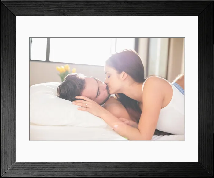 Framed Print : Young couple kissing in bed at home in bedroom