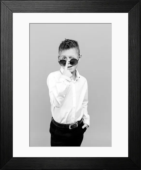 Framed Print : Stylish kid in white shirt and black pants wearing sunglasses posing in studio Framed Print : Stylish kid in white shirt and black pants wearing sunglasses posing in studio