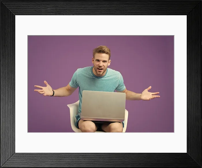 Framed Print : Angry man with laptop on violet background Framed Print : Angry man with laptop on violet background