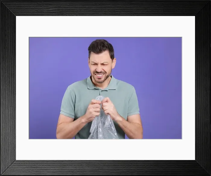 Framed Print : Angry man popping bubble wrap on purple background. Stress relief Framed Print : Angry man popping bubble wrap on purple background. Stress relief