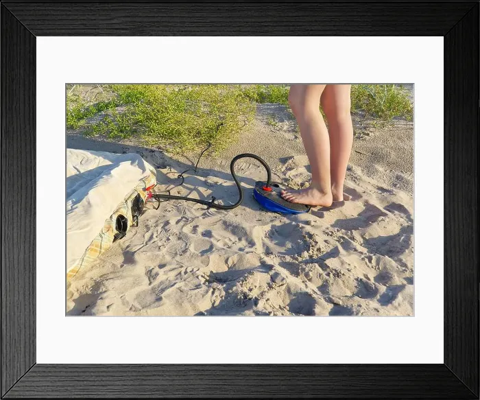 Framed Print : A woman with air foot pump pumps an inflatable mattress or air bed at sandy beach Framed Print : A woman with air foot pump pumps an inflatable mattress or air bed at sandy beach