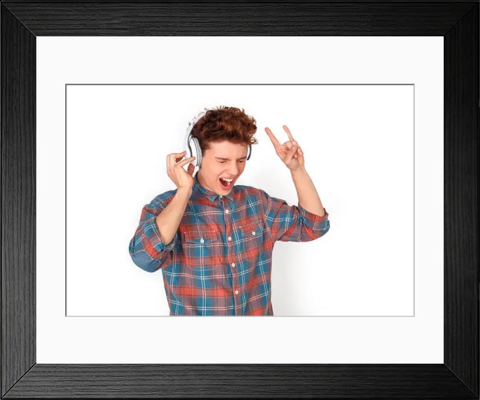 Framed Print : Teenager boy wearing wireless headphones studio standing isolated on white wall listening rock music showing horns Framed Print : Teenager boy wearing wireless headphones studio standing isolated on white wall listening rock music showing horns