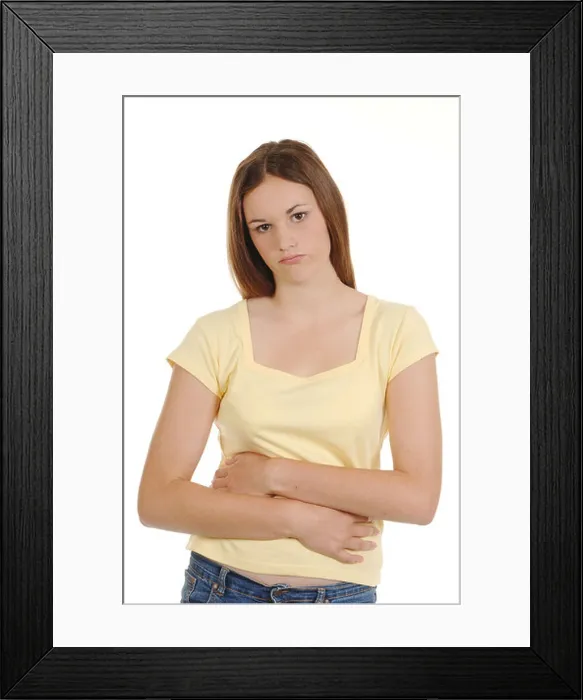 Framed Print : a teenage girl holding her stomach looking in pain Framed Print : a teenage girl holding her stomach looking in pain