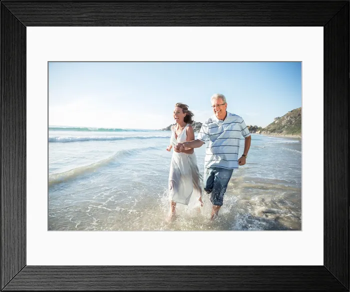 Framed Print : Older couple playing in waves on beach Framed Print : Older couple playing in waves on beach