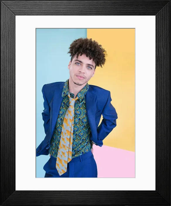 Framed Print : Portrait of a handsome mixed race young man wearing a blue suit and colourful shirt and tie stands in front of a yellow Framed Print : Portrait of a handsome mixed race young man wearing a blue suit and colourful shirt and tie stands in front of a yellow
