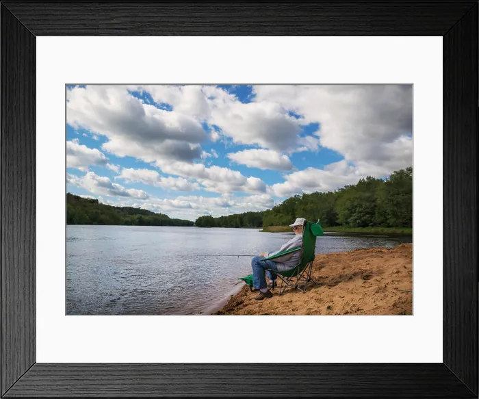 Framed Print : Senior man sitting by the river fishing Framed Print : Senior man sitting by the river fishing