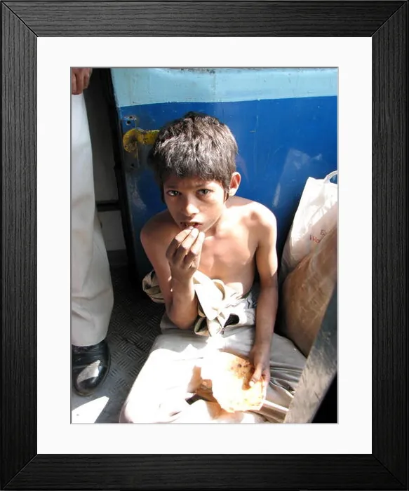 Framed Print : A poor hungry boy eating a stale roti (bread) in an Indian train Framed Print : A poor hungry boy eating a stale roti (bread) in an Indian train