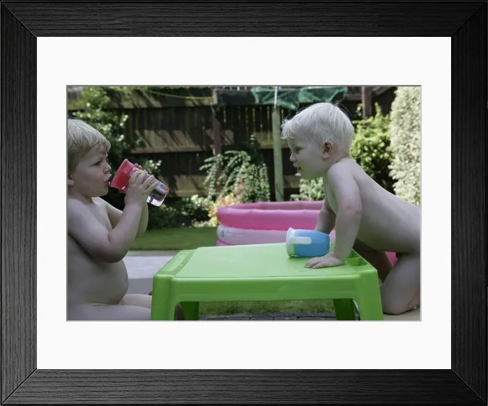 Framed Print : Naked brothers, young male blonde toddler children play at table in garden during English summer sunshine heatwave Framed Print : Naked brothers, young male blonde toddler children play at table in garden during English summer sunshine heatwave