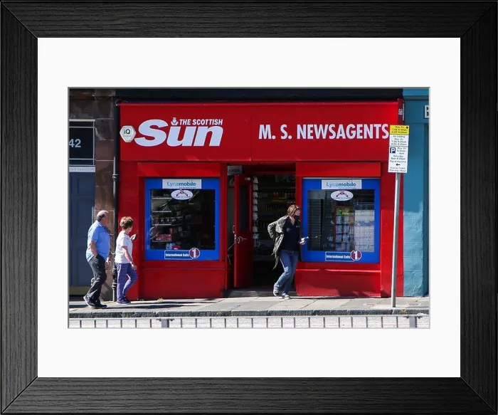 Framed Print : People walks past a newsagent with The Scottish Sun shop fascia in Edinburgh, Scotland Framed Print : People walks past a newsagent with The Scottish Sun shop fascia in Edinburgh, Scotland