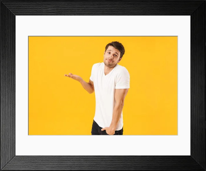 Framed Print : Photo of young man in basic t-shirt looking at camera and throwing up arm isolated over yellow background Framed Print : Photo of young man in basic t-shirt looking at camera and throwing up arm isolated over yellow background
