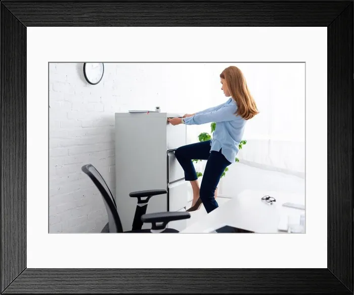 Framed Print : Side view of businesswoman trying to opening cabinet driver near table in office Framed Print : Side view of businesswoman trying to opening cabinet driver near table in office