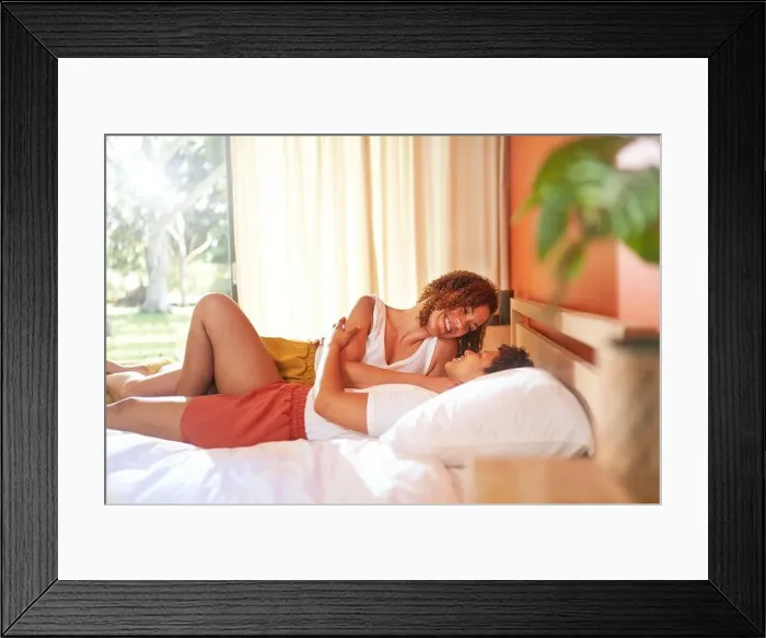 Framed Print : Happy lesbian couple cuddling on bed in morning bedroom