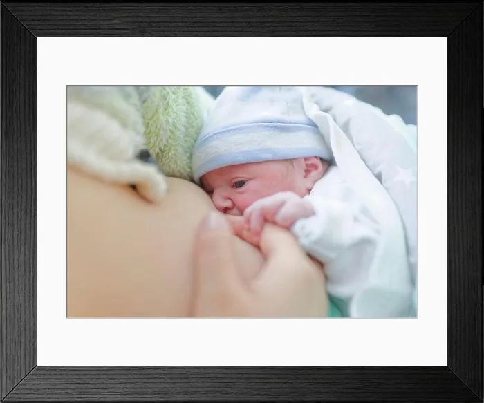 Framed Print : Newborn baby breastfeeding while being gently held by mother in soft natural light Framed Print : Newborn baby breastfeeding while being gently held by mother in soft natural light