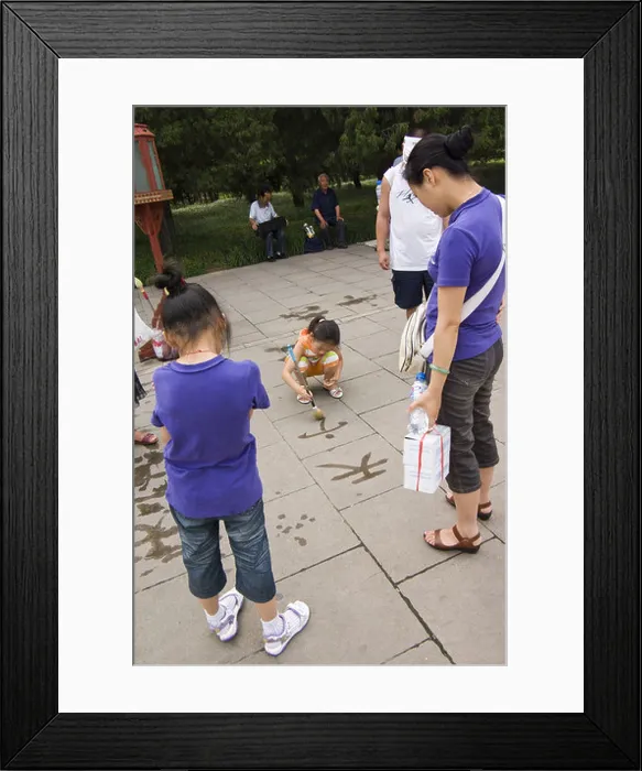 Framed Print : chinese girls practicing calligraphy with water on the pavement in front of the temple of heaven, beijing, china