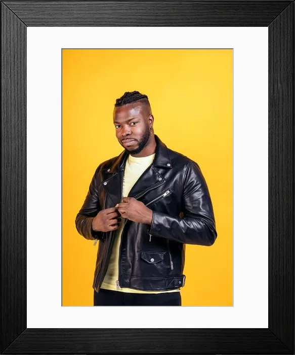 Framed Print : Strong black man wearing black leather jacket posing in studio shot against yellow background