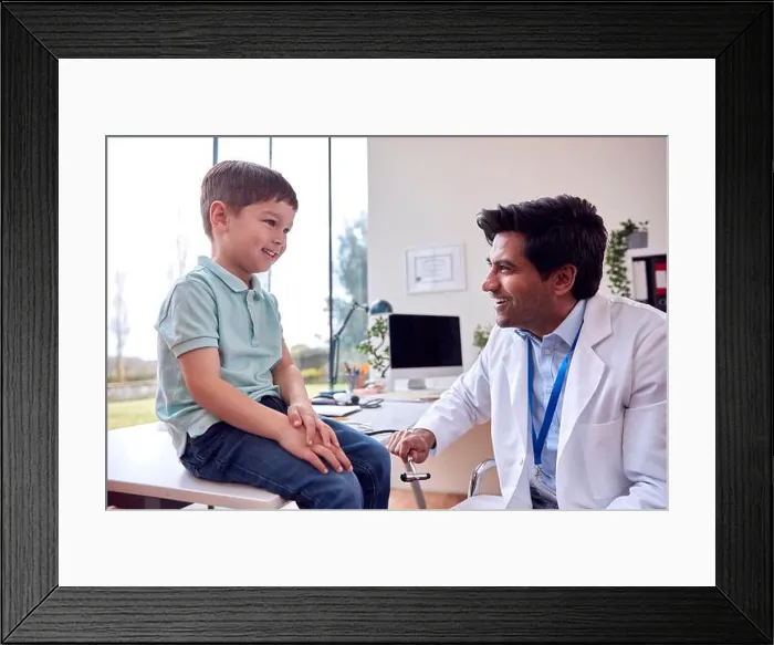 Framed Print : Male Doctor Or GP Wearing White Coat Examining Smiling Boy Testing Reflexes Framed Print : Male Doctor Or GP Wearing White Coat Examining Smiling Boy Testing Reflexes
