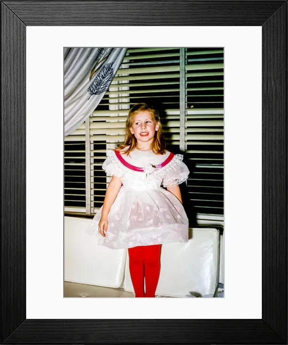 Framed Print : Four year old young girl with blonde hair wearing fancy party dress and red tights standing on a sofa, USA in the 1950s Framed Print : Four year old young girl with blonde hair wearing fancy party dress and red tights standing on a sofa, USA in the 1950s