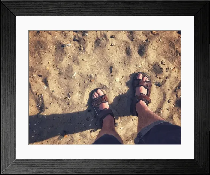 Framed Print : A pair of male feet wearing sandals on a sandy beach Framed Print : A pair of male feet wearing sandals on a sandy beach