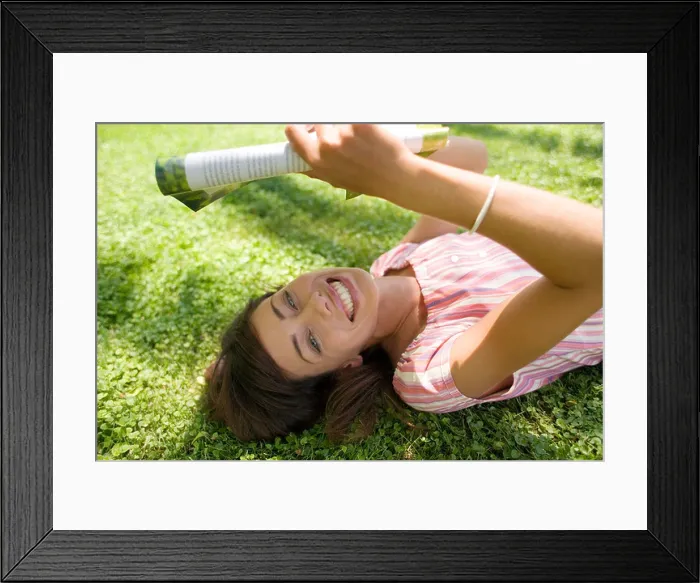 Framed Print : Woman reading in the shade, lying on a lawn Framed Print : Woman reading in the shade, lying on a lawn
