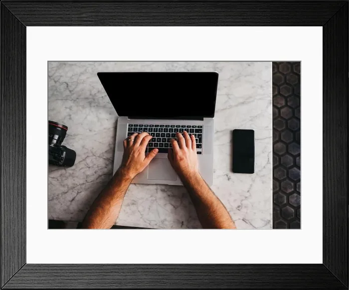 Framed Print : Crop shot from above of man using laptop sitting at marble table with phone near Framed Print : Crop shot from above of man using laptop sitting at marble table with phone near