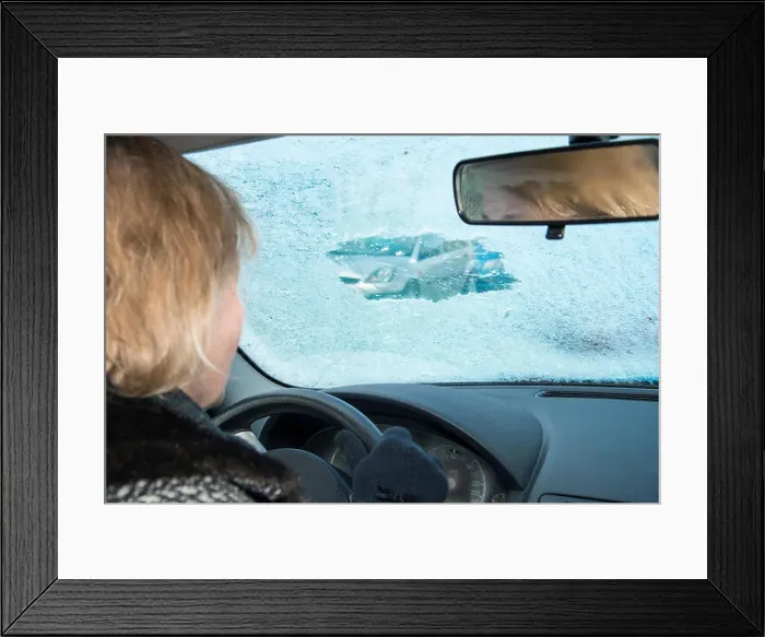 Framed Print : Woman is looking in a car through a small scratched gap in an icy windshield Framed Print : Woman is looking in a car through a small scratched gap in an icy windshield