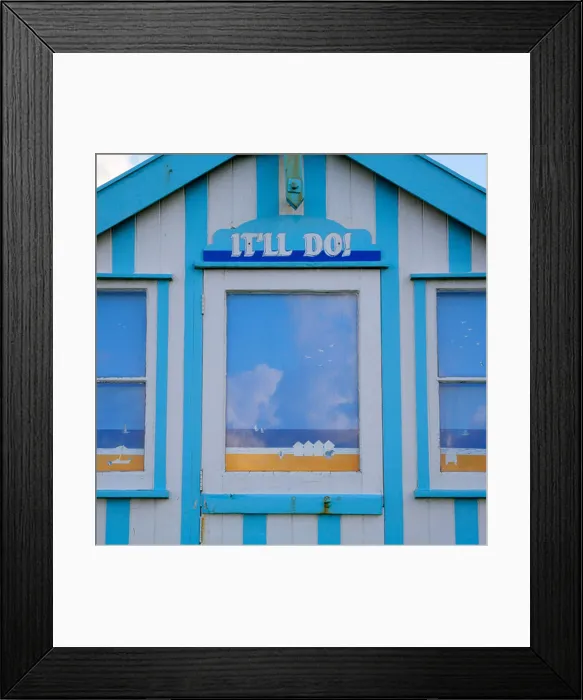 Framed Print : Traditional striped chalet beach hut with seaside scenes painted on windows and 'It'll Do!' name above door Framed Print : Traditional striped chalet beach hut with seaside scenes painted on windows and 'It'll Do!' name above door