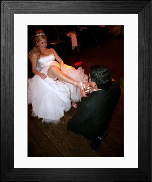 Framed Print : Groom removing garter from bride's leg Framed Print : Groom removing garter from bride's leg