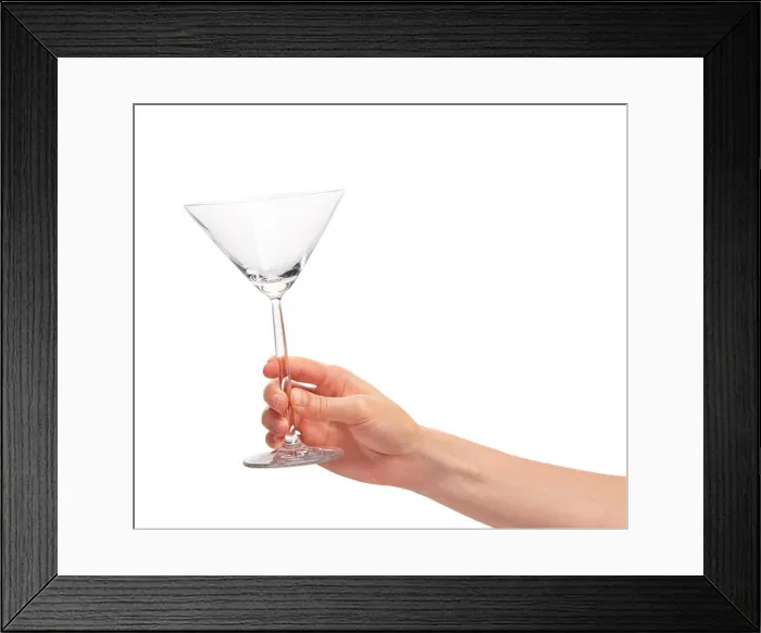 Framed Print : Close up of female hand holding empty clean transparent martini glass against white background Framed Print : Close up of female hand holding empty clean transparent martini glass against white background