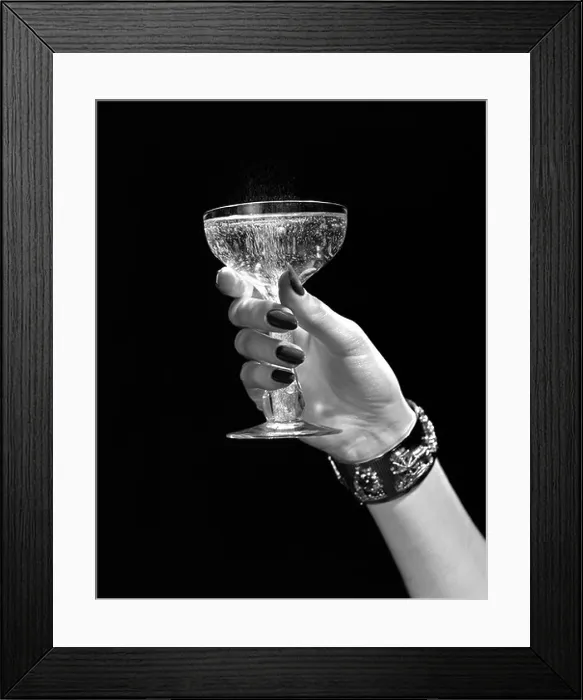 Framed Print : 1930s 1940s 1950s WOMAN HAND ORNATE METAL BRACELET HOLDING UP NEW YEAR TOAST GLASS OF CHAMPAGNE AGAINST BLACK BACKGROUND Framed Print : 1930s 1940s 1950s WOMAN HAND ORNATE METAL BRACELET HOLDING UP NEW YEAR TOAST GLASS OF CHAMPAGNE AGAINST BLACK BACKGROUND