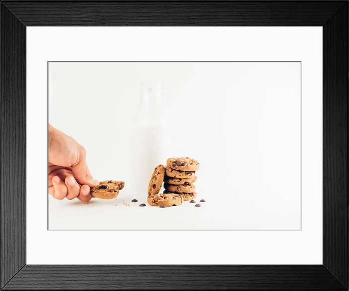 Framed Print : Crop unrecognizable person eating sweet chocolate chips cookies on table with bottle of milk on white background Framed Print : Crop unrecognizable person eating sweet chocolate chips cookies on table with bottle of milk on white background