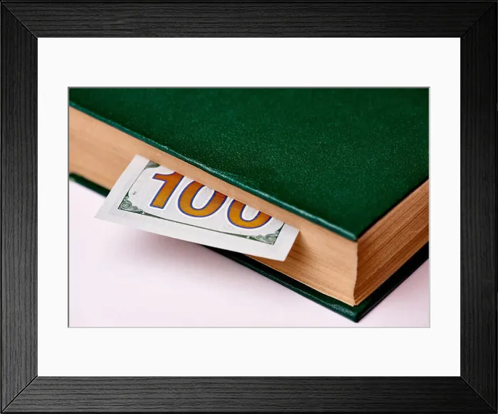 Framed Print : Bill worth one hundred US dollars in book on a white background macro Framed Print : Bill worth one hundred US dollars in book on a white background macro