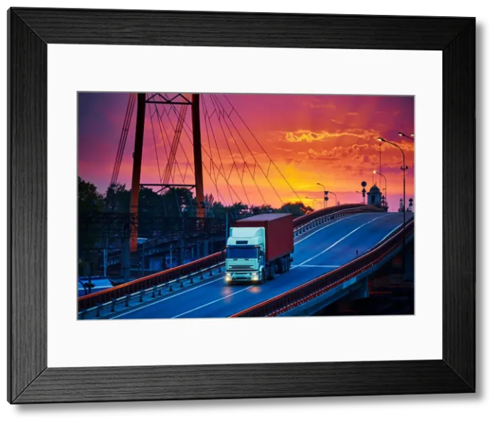Framed Print : truck with container rides over the bridge, beautiful sunset, freight cars in industrial seaport, the road goes up Framed Print : truck with container rides over the bridge, beautiful sunset, freight cars in industrial seaport, the road goes up