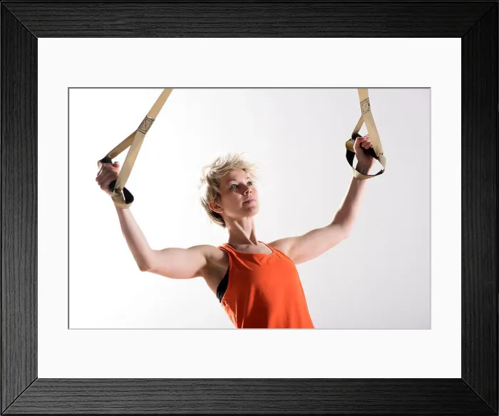 Framed Print : Single strong blond woman in orange sleeveless shirt pulling fitness cords Framed Print : Single strong blond woman in orange sleeveless shirt pulling fitness cords