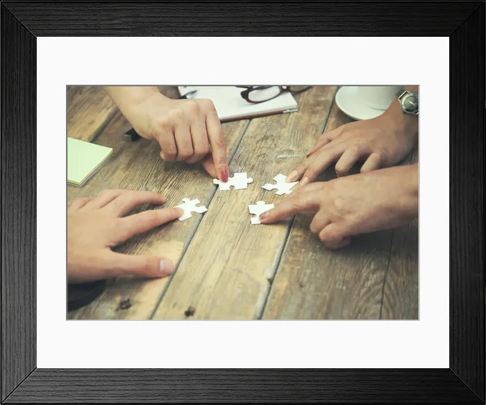 Framed Print : Team work concept, Hands hold puzzles on wood table Framed Print : Team work concept, Hands hold puzzles on wood table
