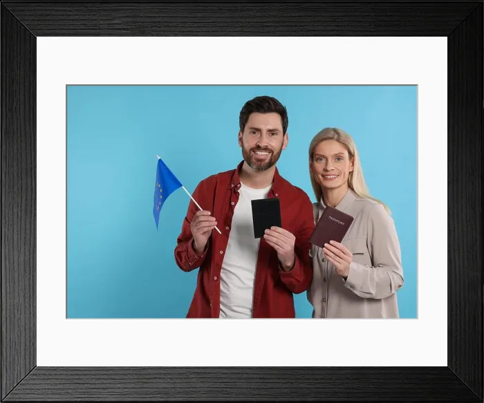Framed Print : Immigration. Happy couple with passports and flag of European Union on light blue background Framed Print : Immigration. Happy couple with passports and flag of European Union on light blue background