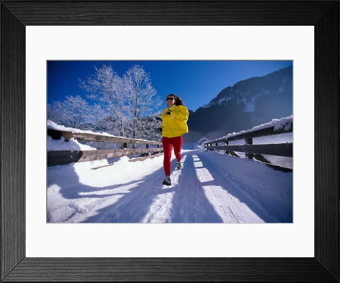 Framed Print : Woman jogging on snow covered track under blue sky Framed Print : Woman jogging on snow covered track under blue sky