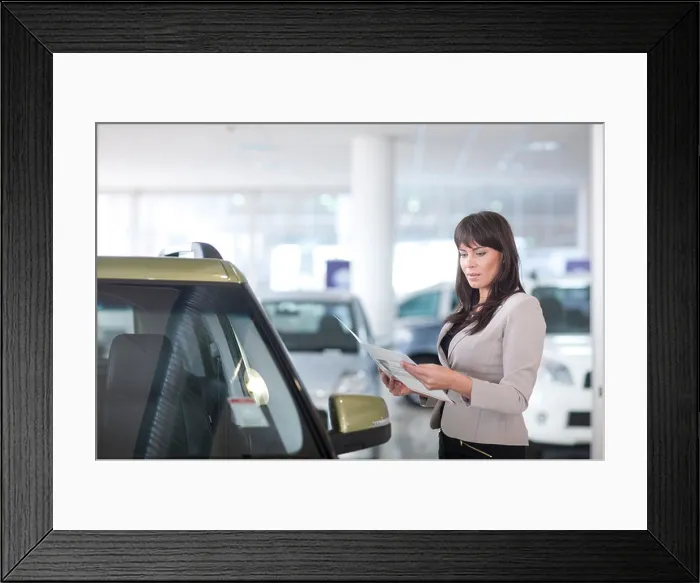 Framed Print : Mid adult woman checking car brochure in showroom