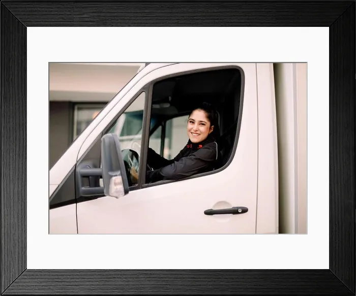 Framed Print : Confident young delivery woman driving truck