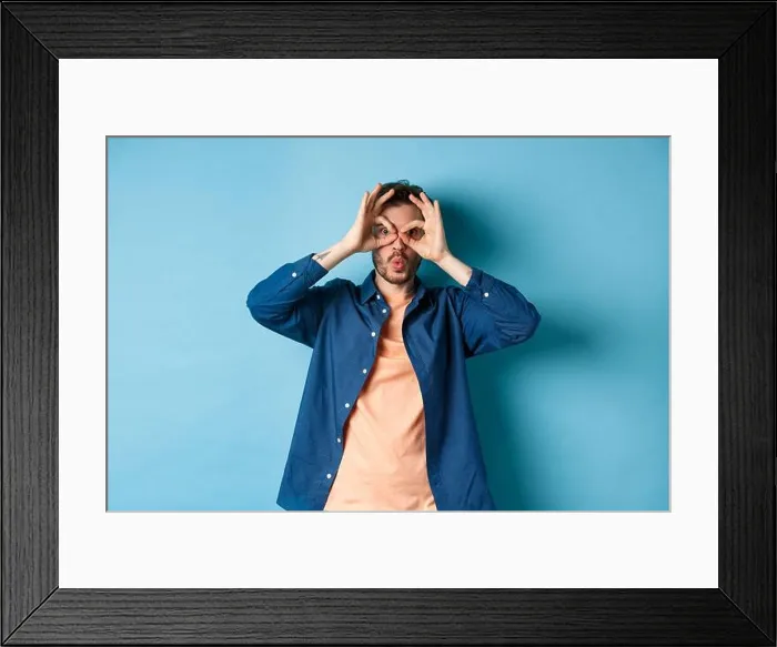 Framed Print : Funny young man looking through hand binoculars and say wow Framed Print : Funny young man looking through hand binoculars and say wow