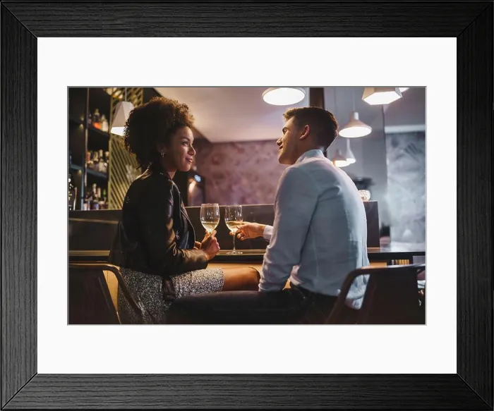 Framed Print : Smiling interracial couple enjoying a romantic wine toast in a cozy bar, celebrating a special moment together Framed Print : Smiling interracial couple enjoying a romantic wine toast in a cozy bar, celebrating a special moment together